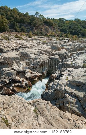 At the foot of the hill on which La Roque sur Cèze in France lies swirl spectacular waterfalls and rapids of the Cascades du Sautadet.