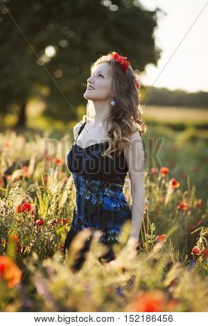 Beautiful young woman on the poppy field in sunlight