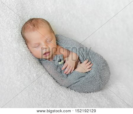 wrapped in gray diaper sleeping baby with opened mouth holding little toy