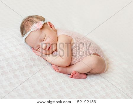 lovely newborn girl sleeping on pink blanket with bare feet
