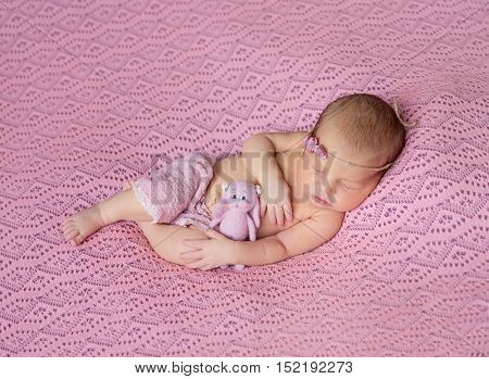 lovely sleeping newborn baby in pink hat and panties on pink blanket