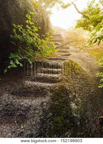 Irregular natural steps carved in the granite rock. Way to the summit illuminated by the sun.