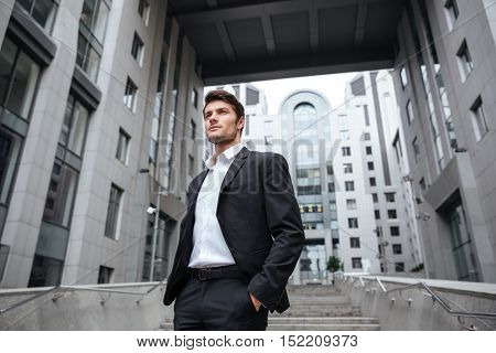 Portrait of handsome young businessman in suit standing near business center