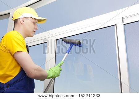 Professional cleaning. Young man washes window
