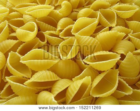 A lot of pasta. Dry pasta. Scattered pasta. Pasta background. Pasta in form of shells. Macaroni products. Macaroni background. Food background.