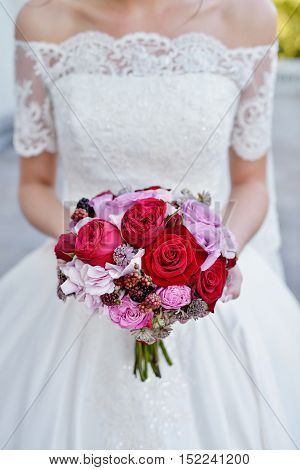 Beautiful bride is holding a wedding colorful bouquet. Beauty of colored flowers. Close-up bunch of florets. Bridal accessories. Female decoration for girl. Details for marriage and for married couple