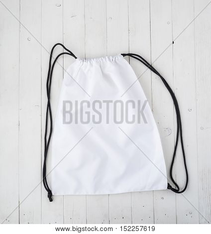 white backpack with black string on planked surface