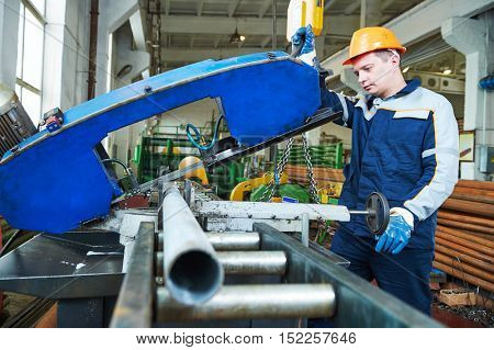 industrial male worker operating bandsaw in manufacturing factory