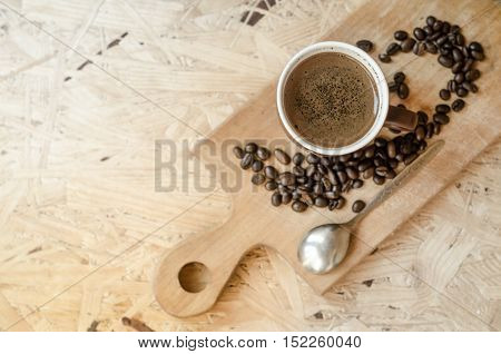 freshly ground coffee brewed in a cup on a wooden board a small spoon