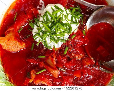 Ucrainian russian traditional vegetarian red soup - borsch in blue plates on wooden background. Top view with soup ladle sore cream and parsley