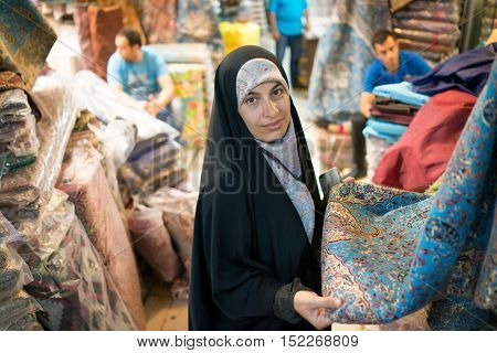 Beautiful Muslim woman spending time on traditional Iranian bazaar market street between people for shopping