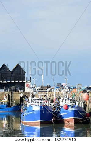 Whitstable United Kingdom -October 1 2016: Fishing Boats in Whitstable Harbour in portrait view with warehouse in background