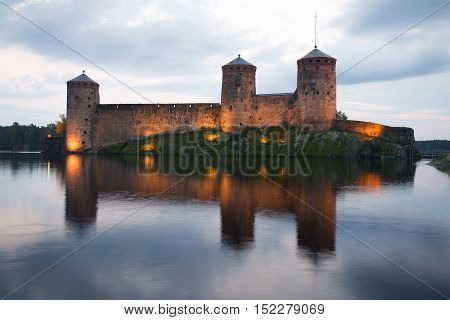 Towers of the medieval fortress Olavinlinna in the background of the cloudy sky. Twilight August in Savonlinna, Finland