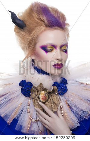 Studio beauty portrait of a girl with blonde hair wearing an undead makeup with purple eye shadows, purple lips and pale skin. Vampire queen halloween costume of a girl wearing a veil