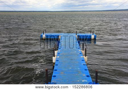 pontoon floating dock from blue plastic pontoons on a lake with waves