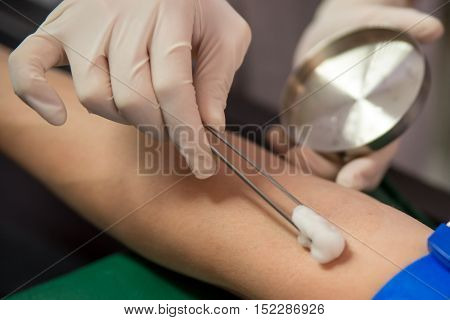 A doctor disinfects the forearm of a patient before performing a venipuncture. Healthcare and medicine concept.
