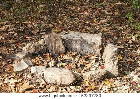 Manmade stone unlit open fireplace in nature in autumn