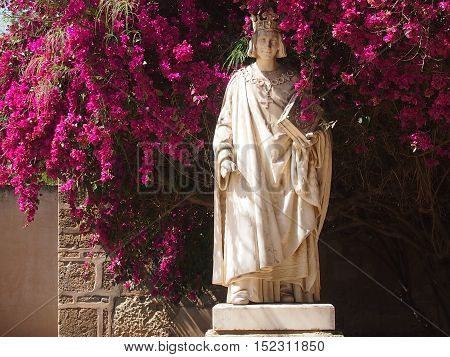 Marble statue among bushes of the blossoming azalea
