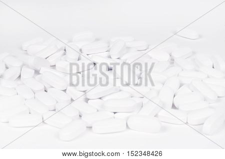 Heap of white pills on a white background Healthcare and Medicin