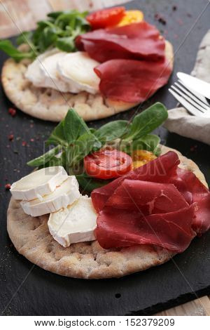 Swedish flatbread hallakaka with sliced ham, Sainte Maure cheese, tomato and lettuce