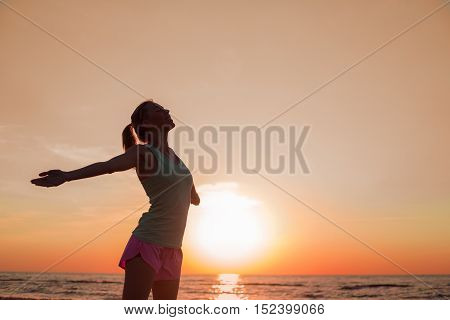 Happy woman after workout standing in the sunset