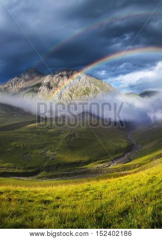 Rainbow in mountain valley during sunset. Beautiful natural landscape