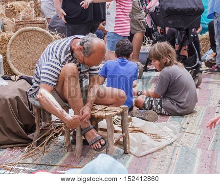 Elderly Man Weaves Chair At The Fair
