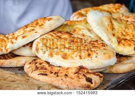 Georgian traditional dish khachapuri, pastry flat cake cheese-filled bread fried on the grill, BBQ. Fresh hot tasty street food in the market. Cooking food. Preparation dish of Middle Eastern cuisine.