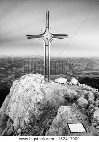 Cross Raised  At Alpine Mountain Peaksharp Rocks, Sun In Sky.