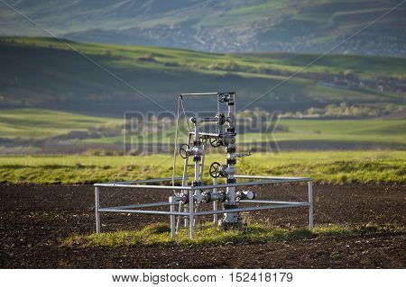 Natural gas wellhead in a meadow of green grassland field