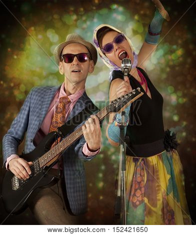 Rockabilly couple having fun playing the guitar and singing in front of colorful background