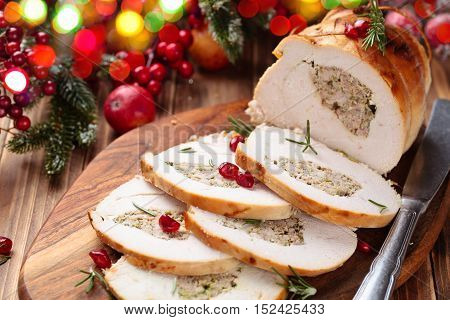 Stuffed turkey breast with pomegranate and rosemary on cutting board.