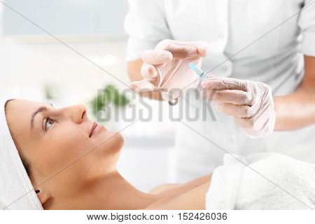 Cosmetic ampoule, a woman in the beauty salon, vitamin C in cosmetic ampoule.