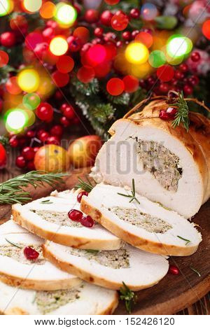 Stuffed turkey breast with pomegranate and rosemary on cutting board.