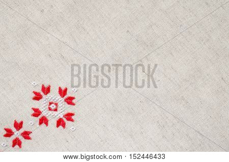 Element handmade embroidery on flax by red and white cotton threads. Design of ethnic textures. Background with embroidery. Geometric ornament.