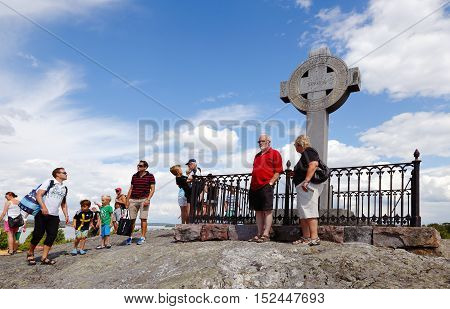 Bjorko, Sweden - July 19, 2014: People at Ansgar monument in the shape of a Celtic cross as the 1000 anniversary of the missionary Ansgar's arrival at Birka erected the cross in 1834 on Bjorko island Sweden.