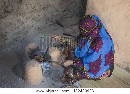 Nizwa Oman October 13th 2016: omani lady roasting coffee in fire in a traditional kitchen