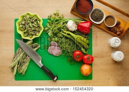 Fresh vegetables prepared for cooking, vegan meal, green beans. Menu for healthy lifestyle, ingredients for cooking salad with spices in kitchen with knife for cutting food.