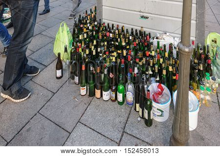 STRASBOURG FRANCE - DEC 15 2013: Multiple wine and beer bottles near glass recycle bin in urban enviroment in the french city of Strasbourg France