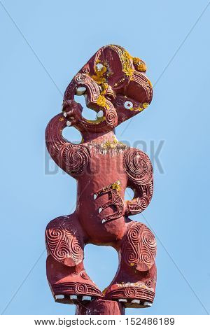 isolated Maori wooden totem pole against blue sky