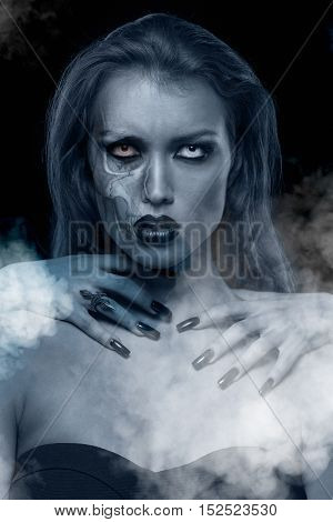 Closeup portrait of a pretty gothic woman with hands of vampire on her neck on black background