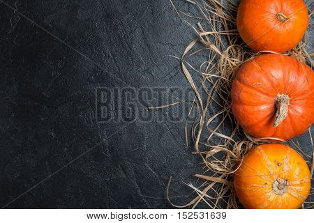 Autumn Pumpkin Thanksgiving Background - orange pumpkins over black table, top view
