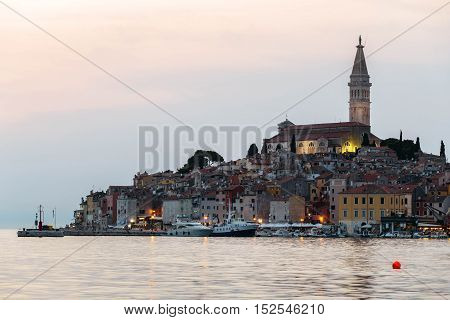 View of the historic part of Rovinj in Croatia during sunset. Above the town rises the Church of St. Euphemia. On the sea the ships.
