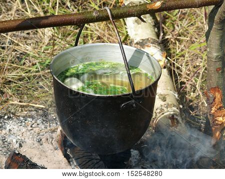 fish soup a bowler hat over a campfire after a successful fishing.
