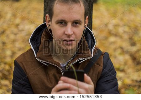 Young man listening to music on smartphone on the nature