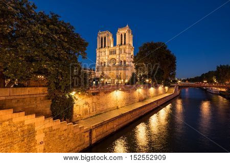 Notre Dame de Paris cathedral illuminated at twilight with the Seine River and the Pont au Double on Ile de La Cite. Summer evening in the 4th Arrondissement Paris France