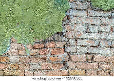 green plaster has cracked to reveal a worn brick wall below street wall background texture .