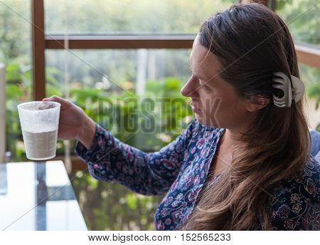 Young girl lookıng at a cup of flour half-face