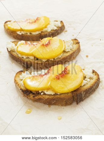 Fresh peach crostini with honey and ricotta cheese selective focus vertical