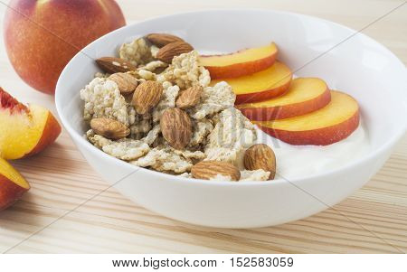 Whole grain cereal with fresh peach fruit yogurt and almond in white bowl. Healthy breakfast. Health and diet concept selective focus horizontal